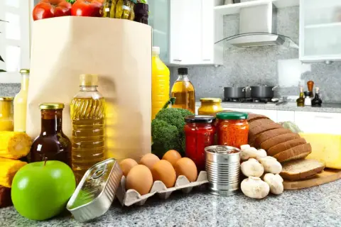 Un sacco di carta pieno di pomodori, uova, pane, formaggio e altri cibi proteici, pronti per essere cucinati.